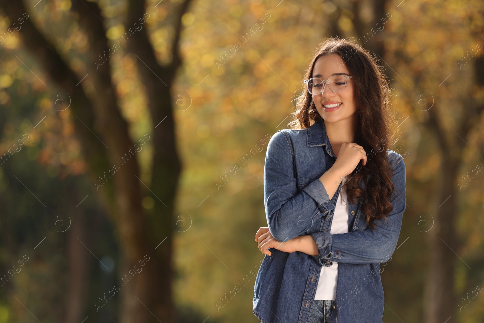 Photo of Young woman wearing eyeglasses in autumn park, space for text