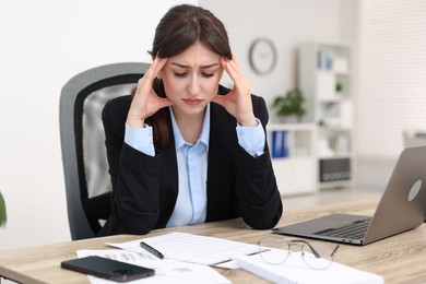 Overwhelmed woman suffering at table in office