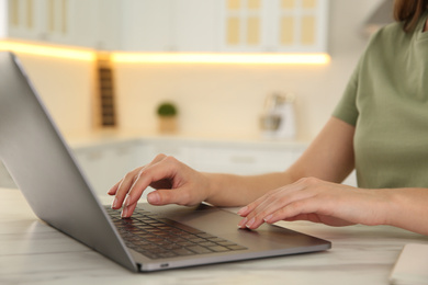 Woman working with modern laptop at marble table, closeup