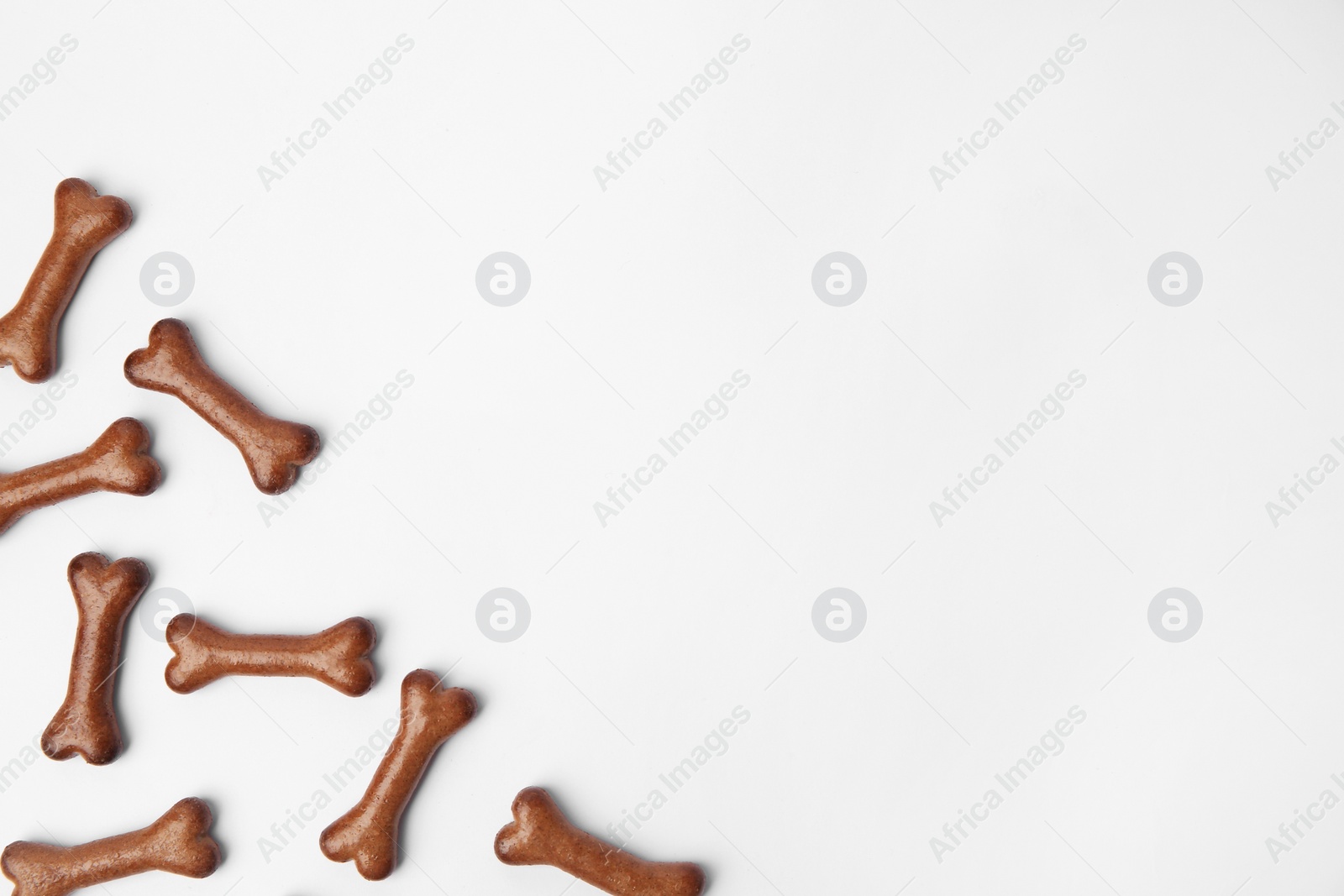 Photo of Bone shaped dog cookies on white background, flat lay. Space for text