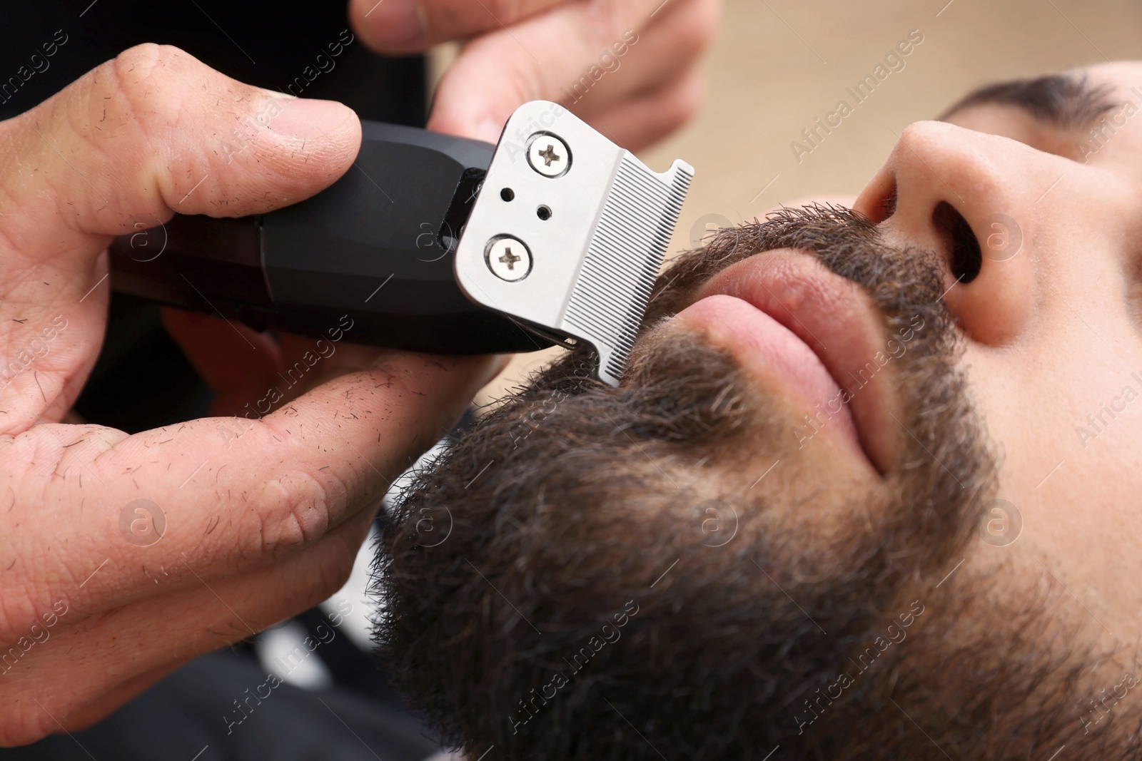 Photo of Professional hairdresser working with client in barbershop, closeup