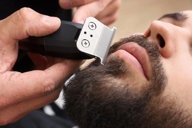 Professional hairdresser working with client in barbershop, closeup