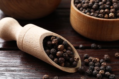 Photo of Aromatic spice. Whole black pepper on wooden table, closeup