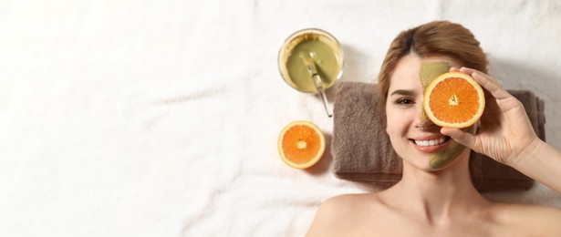 Image of Woman with mask on face and cut orange relaxing in spa salon, top view with space for text. Banner design