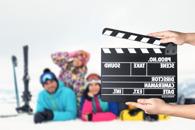 Image of Assistant holding clapperboard and people in snowy mountains, closeup. Cinema production 