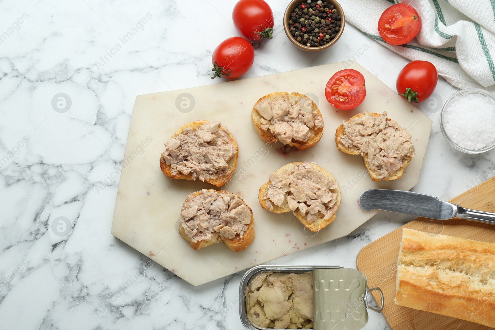 Photo of Tasty sandwiches with cod liver on white marble table, flat lay. Space for text