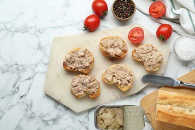 Photo of Tasty sandwiches with cod liver on white marble table, flat lay. Space for text