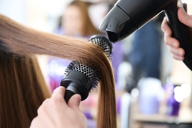 Photo of Professional hairdresser working with client in salon