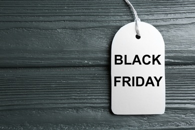 Photo of Top view of blank white tag on dark wooden background, space for text. Black Friday concept