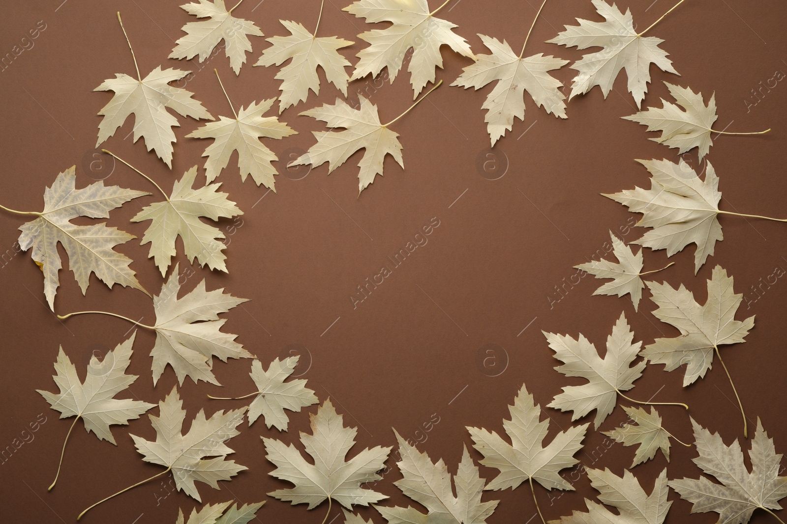 Photo of Frame of dry autumn leaves on brown background, flat lay. Space for text