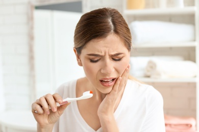 Photo of Young woman suffering from toothache indoors