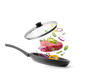 Image of Different vegetables and beef slice falling into frying pan on white background. Process of cooking