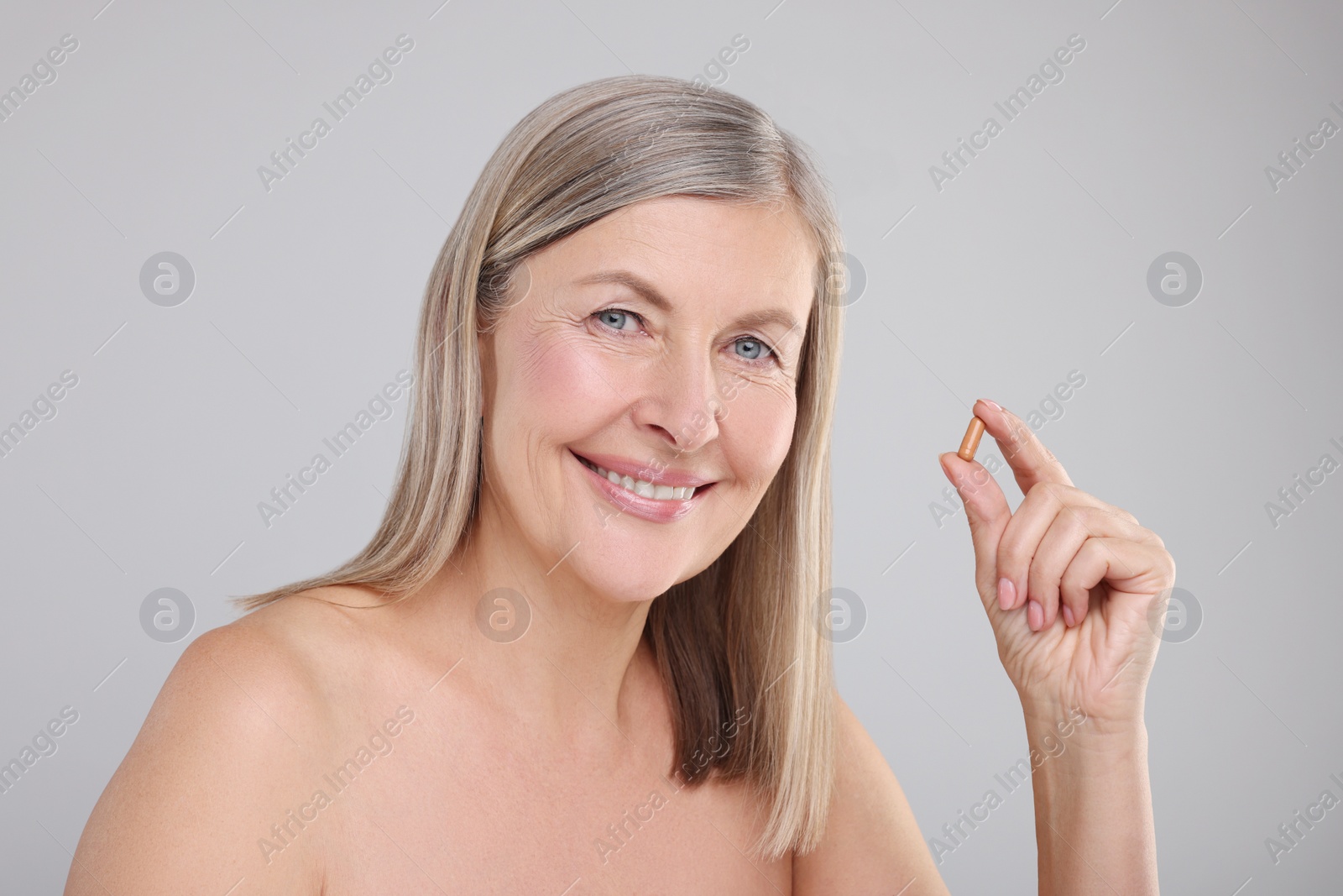 Photo of Beautiful woman with vitamin capsule on grey background