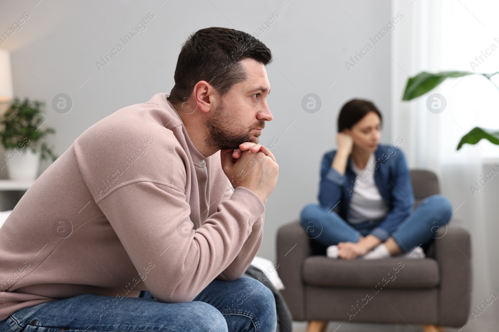 Photo of Offended couple ignoring each other after quarrel in bedroom, selective focus. Relationship problems