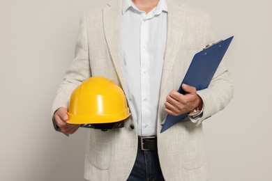 Photo of Professional engineer with hard hat and clipboard on white background, closeup