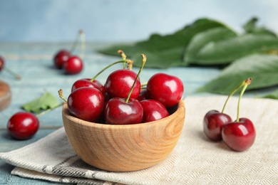 Photo of Wooden bowl with ripe sweet cherries on table