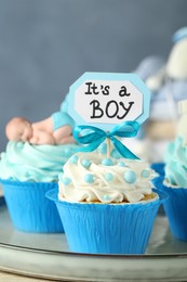 Photo of Beautifully decorated baby shower cupcakes for boy with cream on tray, closeup view