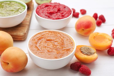 Photo of Different puree in bowls and fresh fruits on white wooden table