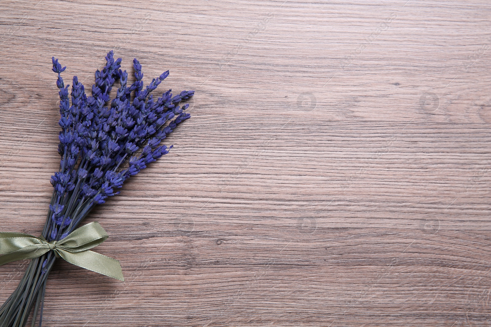 Photo of Bouquet of beautiful preserved lavender flowers on wooden table, top view. Space for text