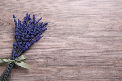 Photo of Bouquet of beautiful preserved lavender flowers on wooden table, top view. Space for text