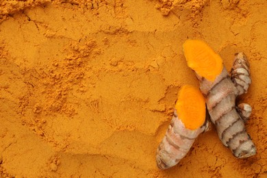 Photo of Cut raw root on aromatic turmeric powder, top view. Space for text