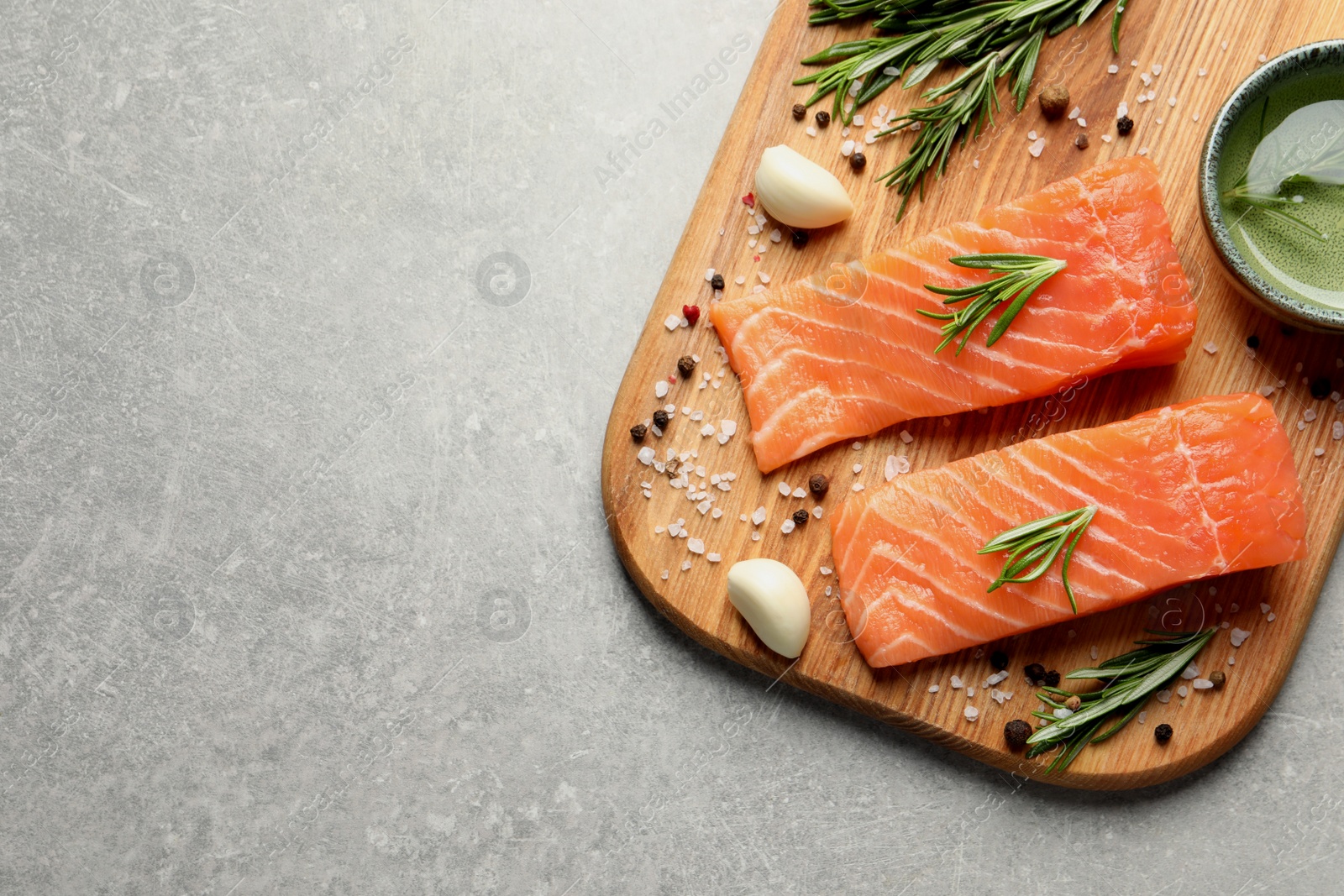 Photo of Fresh raw salmon and spices on light grey table, top view. Space for text