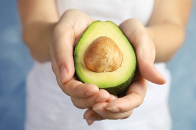 Woman holding half of ripe fresh avocado, closeup