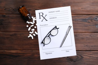 Medical prescription form with empty fields, glasses, pills and pen on wooden table, flat lay