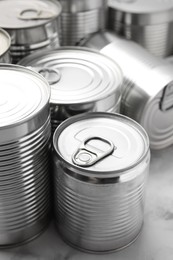 Photo of Many closed tin cans on white marble table, closeup