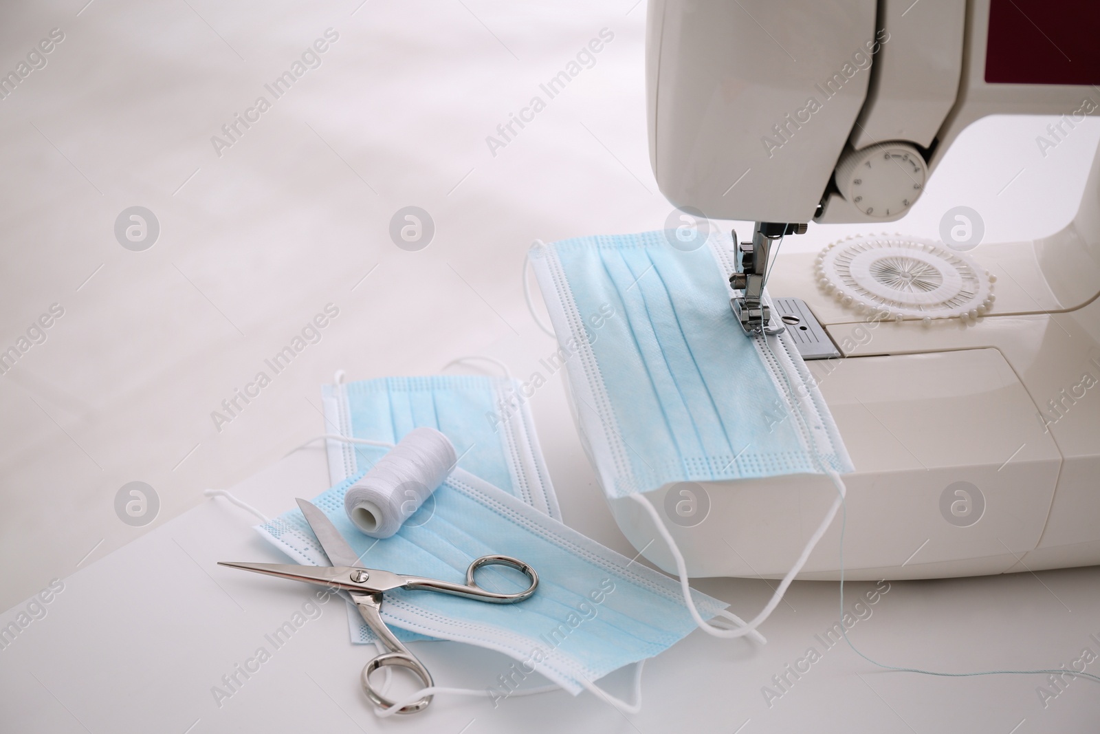 Photo of Sewing machine with disposable face mask on table, space for text