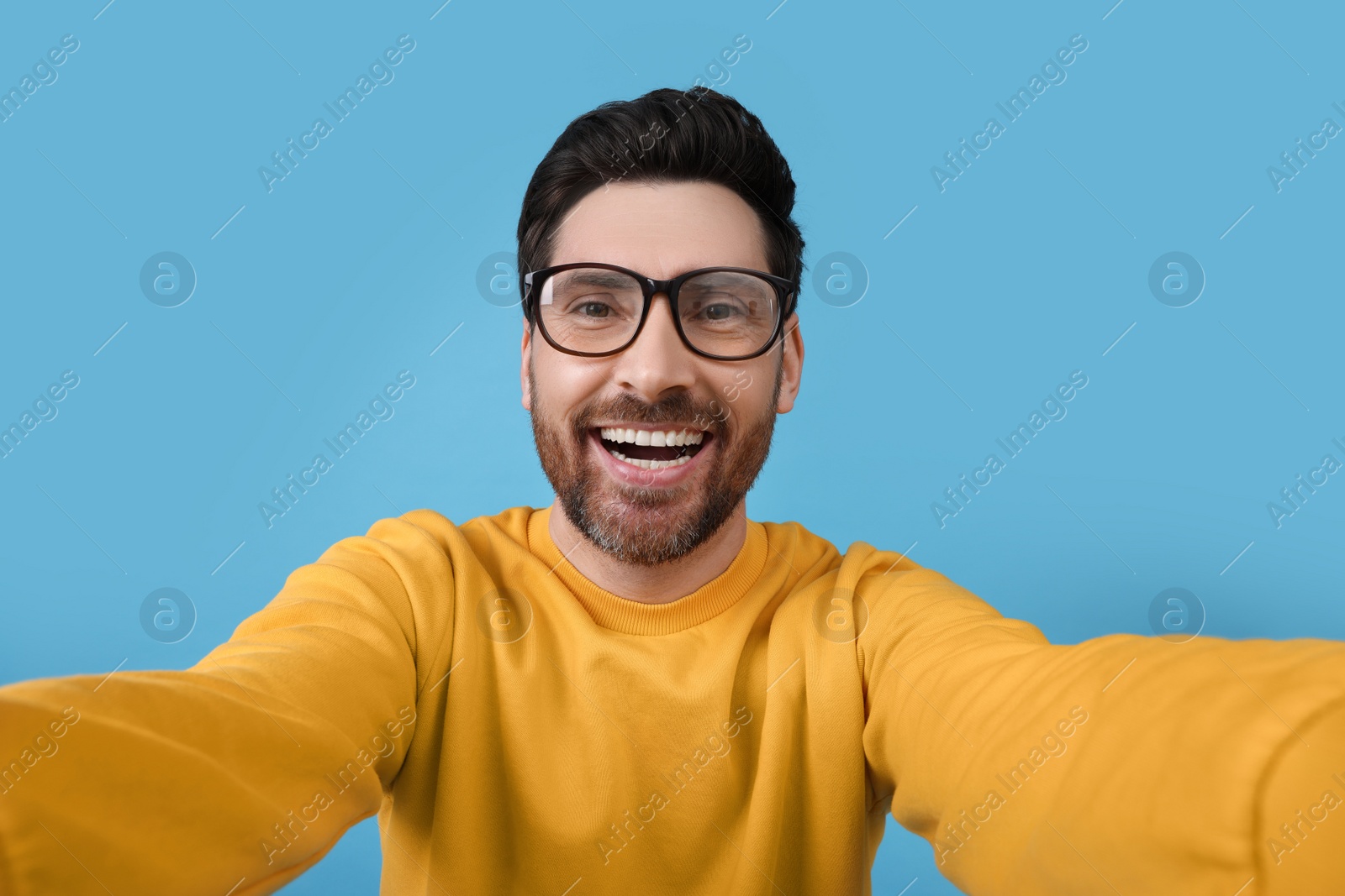 Photo of Smiling man taking selfie on light blue background