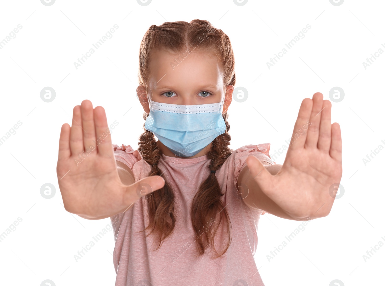 Photo of Little girl in protective mask showing stop gesture on white background. Prevent spreading of coronavirus