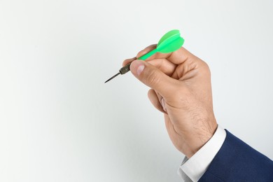 Photo of Man holding green dart on light background, closeup. Space for text