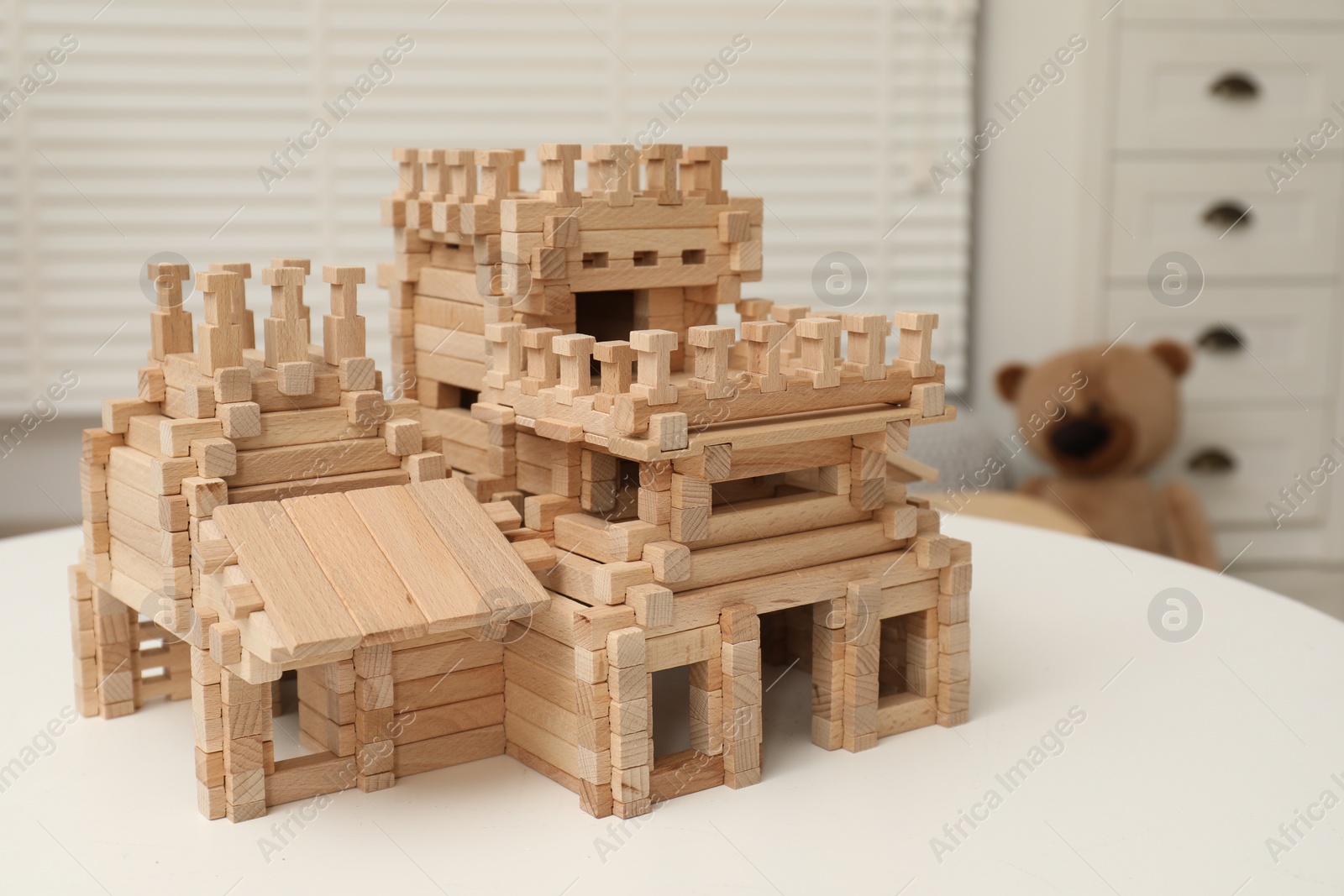 Photo of Wooden castle on white table indoors. Children's toy