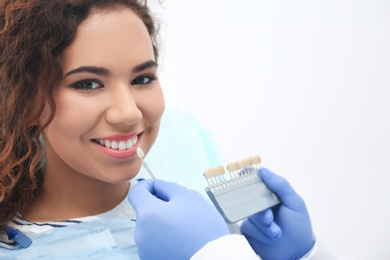 Dentist matching patient's teeth color with palette in office. Space for text