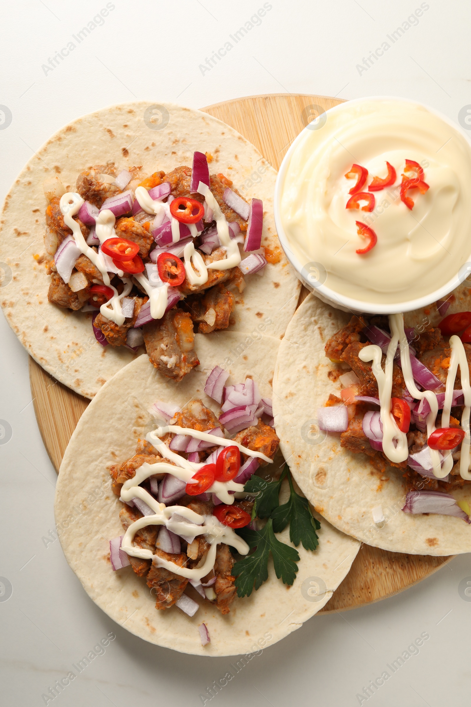 Photo of Delicious tacos with vegetables, meat and sauce on white marble table, top view