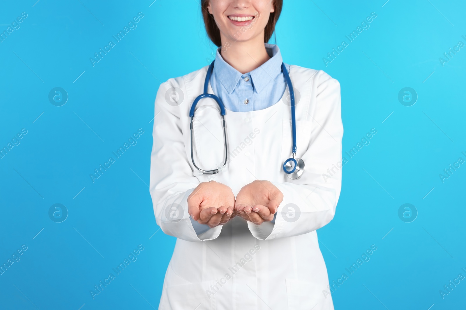 Photo of Female doctor showing open hands on color background, closeup