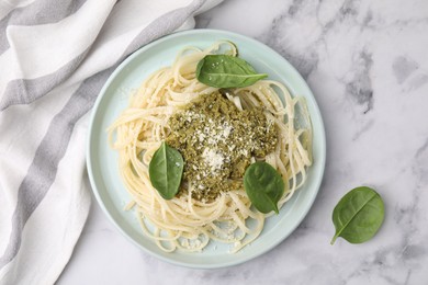 Photo of Tasty pasta with spinach, cheese and sauce on white marble table, top view