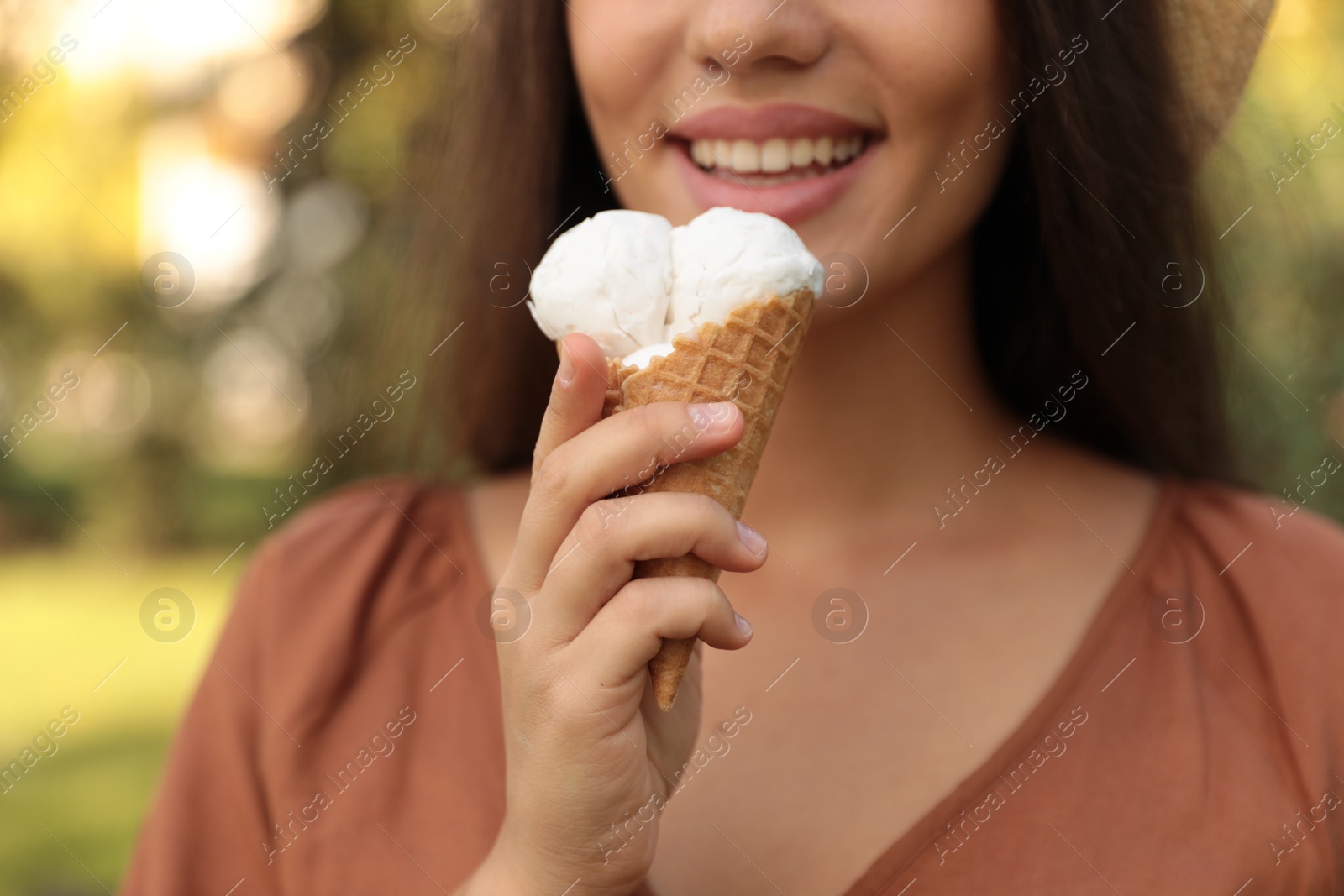 Photo of Young woman with delicious ice cream in waffle cone outdoors, closeup