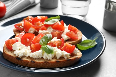 Photo of Plate with tasty bruschettas on grey table, closeup