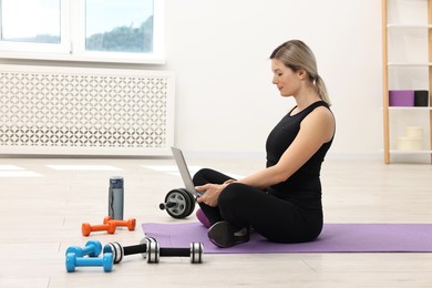 Photo of Online fitness trainer. Woman watching tutorial on laptop at home