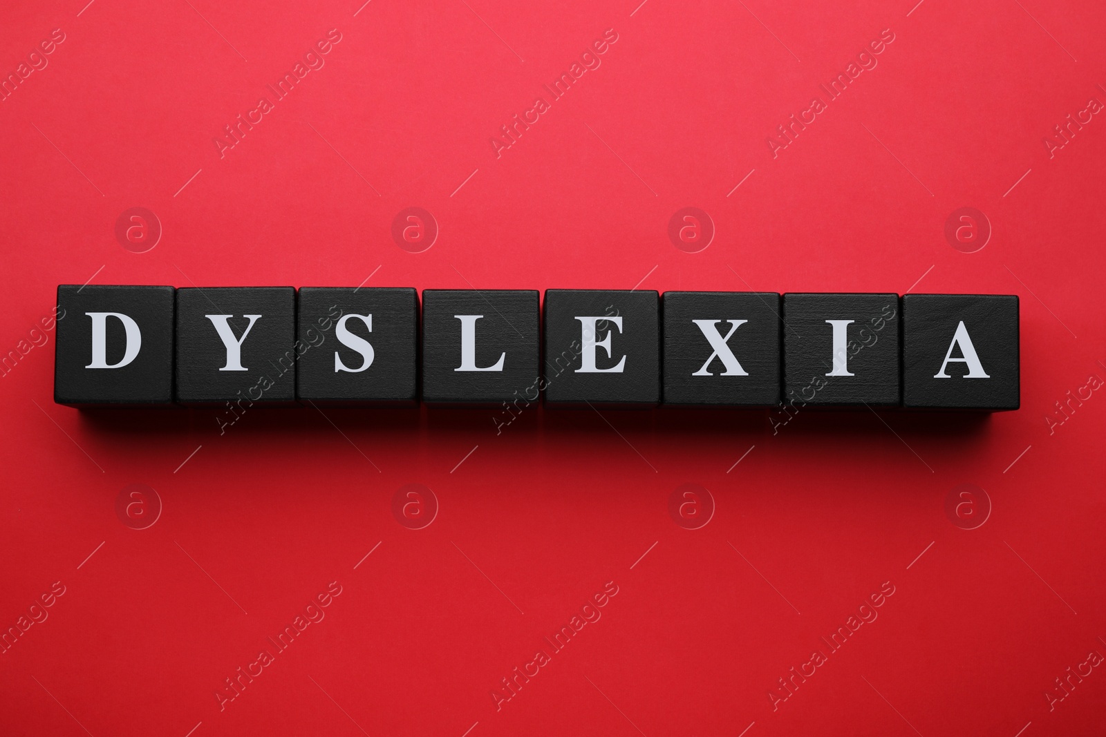 Photo of Wooden cubes with word Dyslexia on red background, flat lay