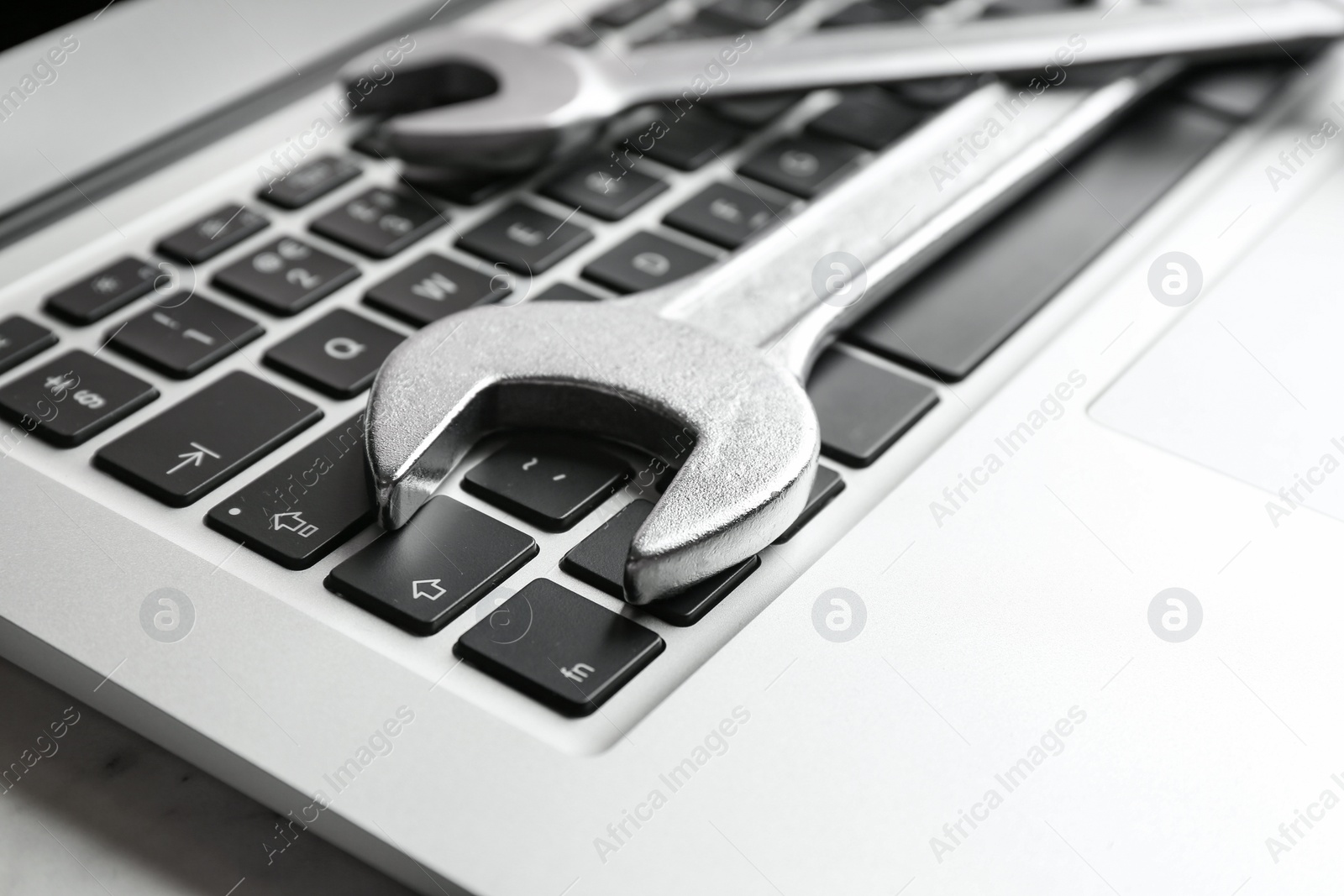 Photo of Laptop and spanners on table, closeup. Concept of technical support