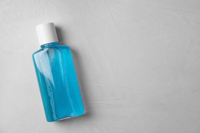 Photo of Fresh mouthwash in bottle on grey textured background, top view. Space for text