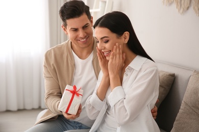 Man presenting gift to his beloved woman at home. Valentine's day celebration