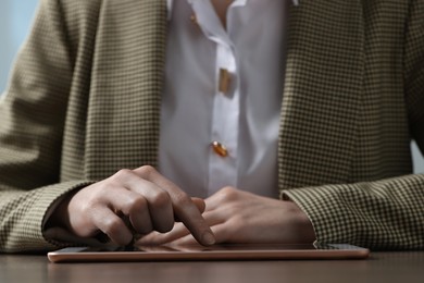 Closeup view of woman using modern tablet at wooden table