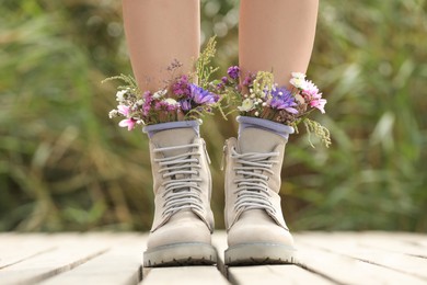 Photo of Woman standing on wooden pier with flowers in socks outdoors, closeup