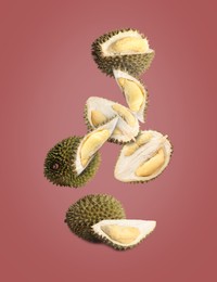 Image of Fresh ripe durians falling on pale burgundy background