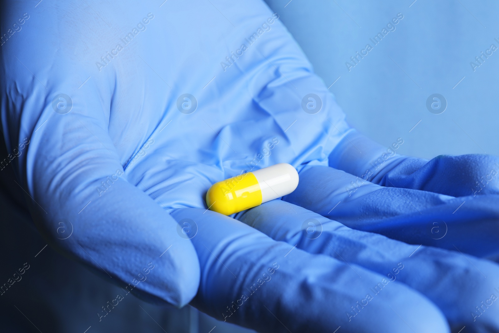 Photo of Doctor in medical glove holding pill, closeup view