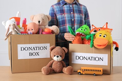 Photo of Little boy near donation boxes with toys against light background, closeup